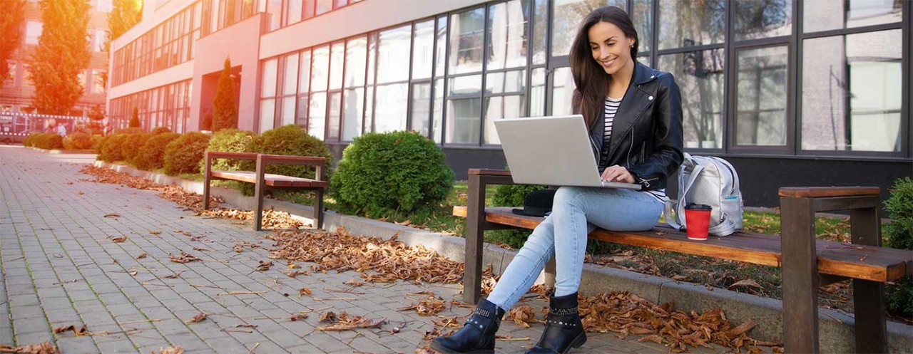 Woman sitting on a bench with her laptop.