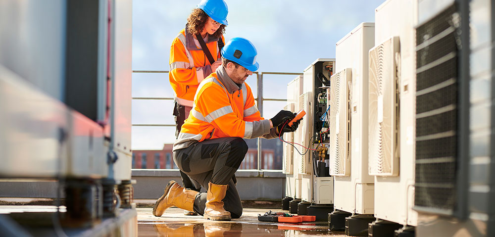 Electricians working outside using a multimeter.