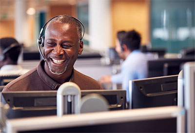 Man talking on the phone at computer with a headset.
