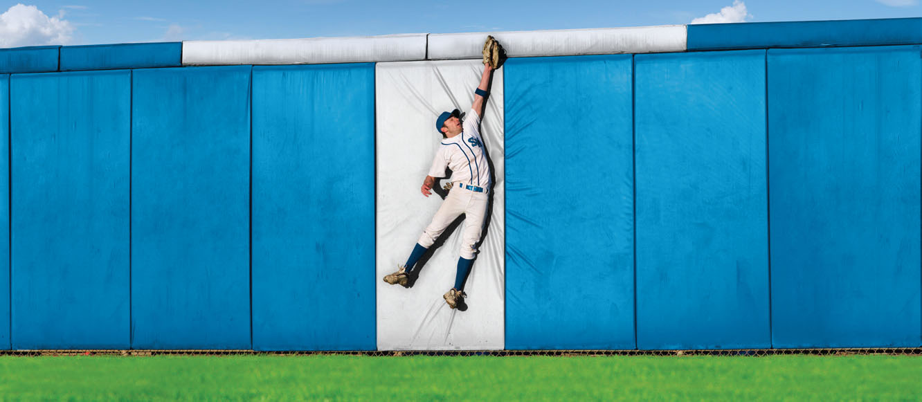 Player catching baseball at the wall painted with a white T.