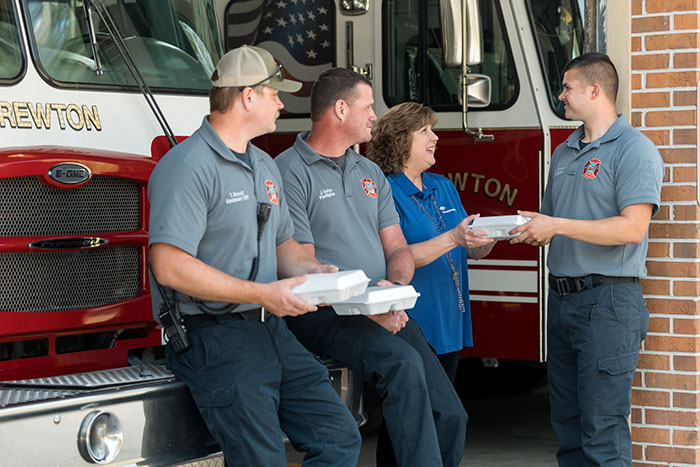 Trustmark employee handing out meals to firemen at a fire station.