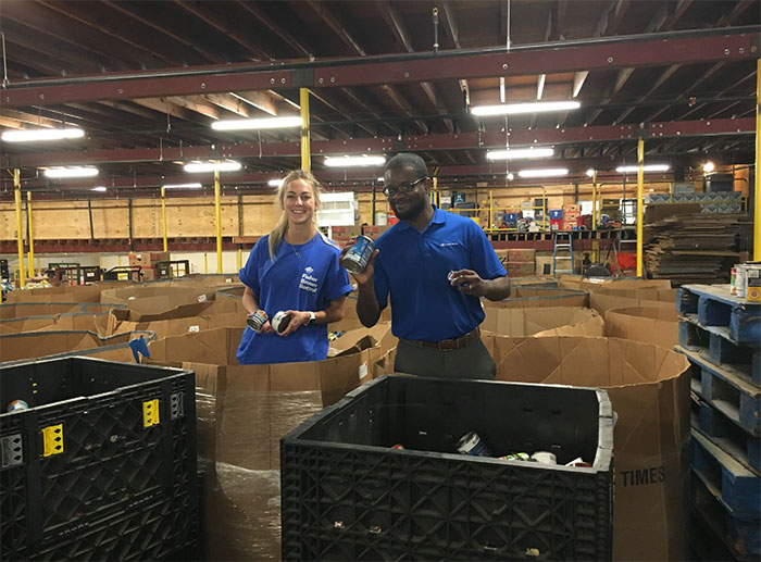 Volunteer female and male packing boxes at a canned food collection