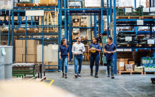 Four employees walking through a warehouse