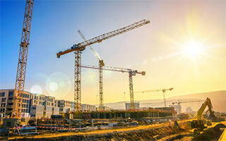 Construction cranes over a city skyline