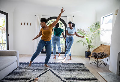Three young women dancing in home.