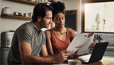 Couple sitting in the kitchen looking at papers.