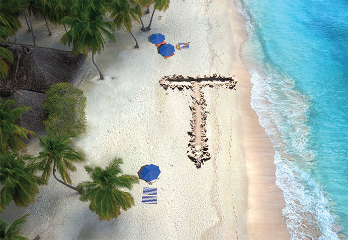 Overhead view of a beach with the letter 'T' carved in the sand.