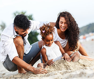 Family playing in sand at beach.