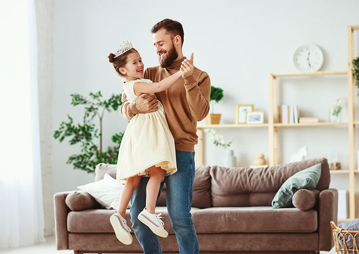 Father and daughter dancing in living room.