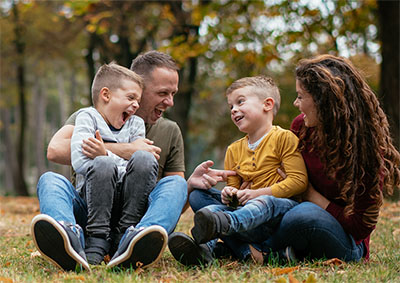 Young family sitting in a field and laughing.