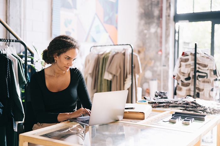 woman working on her laptop in a clothing boutique