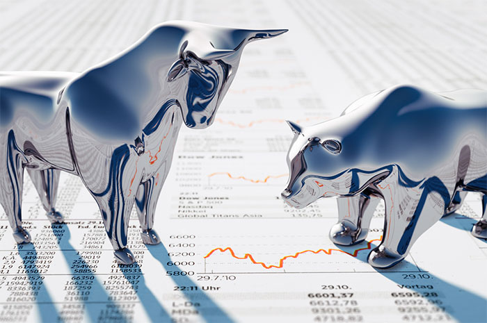Bull and bear statues on a stock chart.